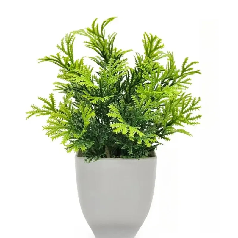 An artificial fern-like plant with vibrant green leaves in a smooth, minimalist matte white pot against a white background.