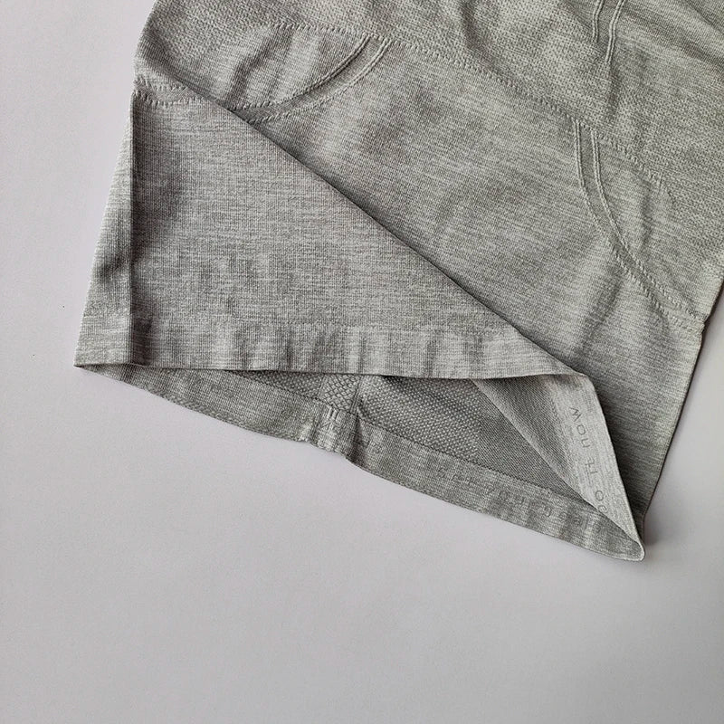 Close-up of a light grey seamless athletic top with textured ventilation panels and a fitted hem.