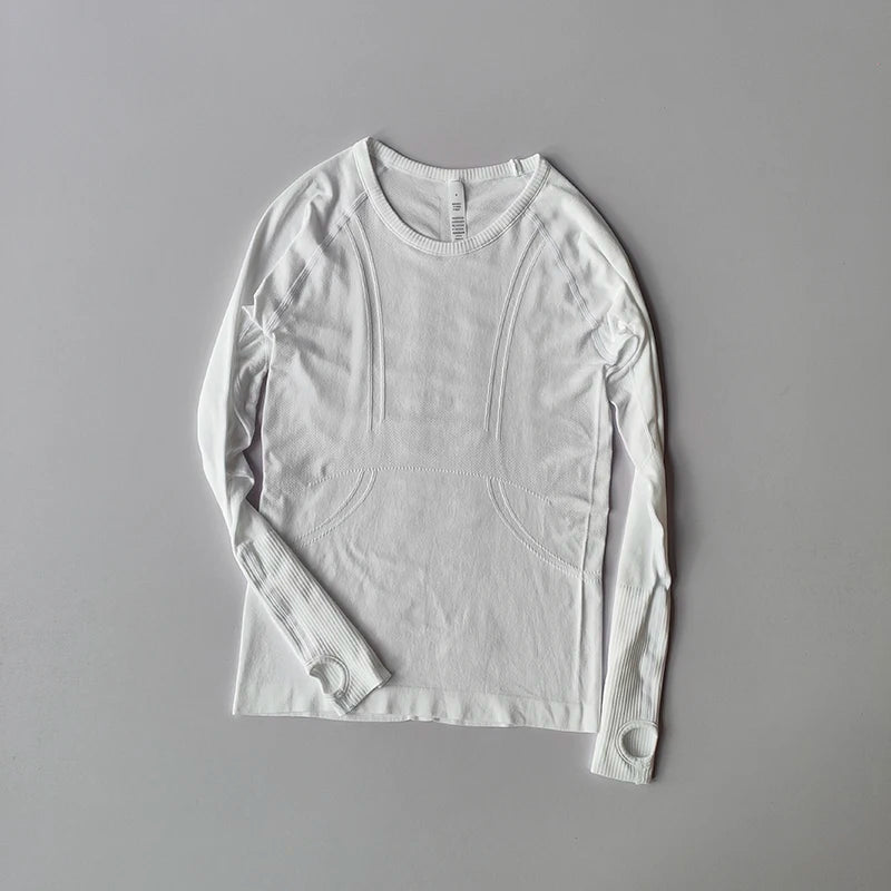 White seamless long-sleeve gym top with ribbed details and integrated thumbholes on a grey background.