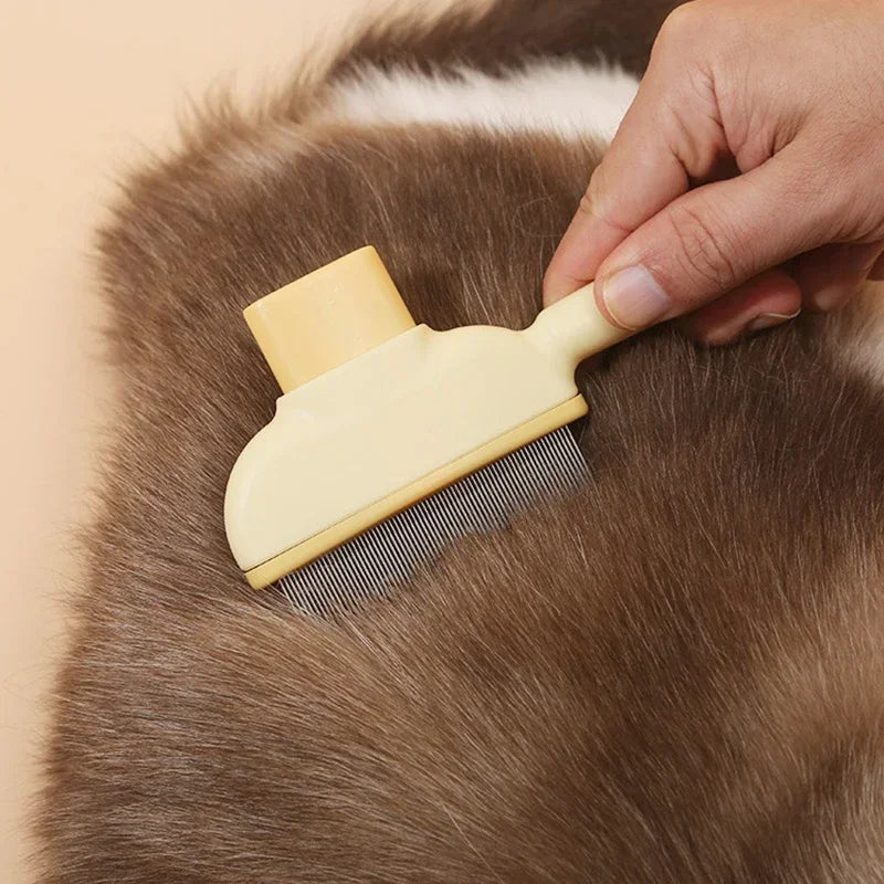 A hand uses a pale yellow, fine-toothed pet grooming comb to brush the brown, fluffy fur of a pet.