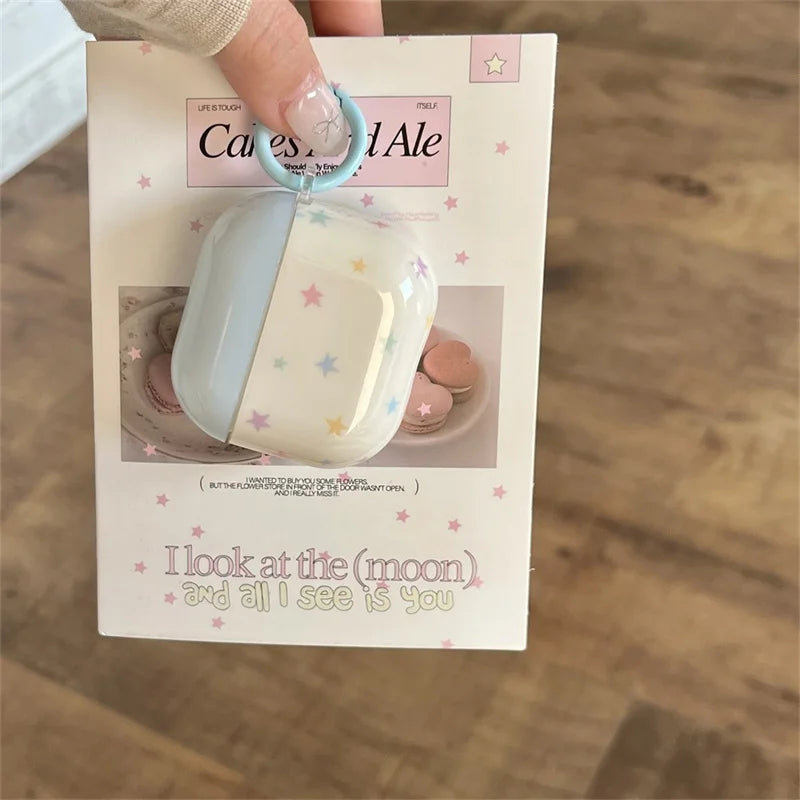 Light blue and clear silicone AirPods case with multicoloured star print and a matching ring clip.