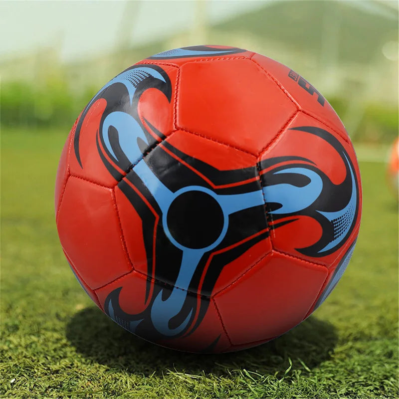 Red football with a black and blue graphic flame-style pattern on a grass pitch background.
