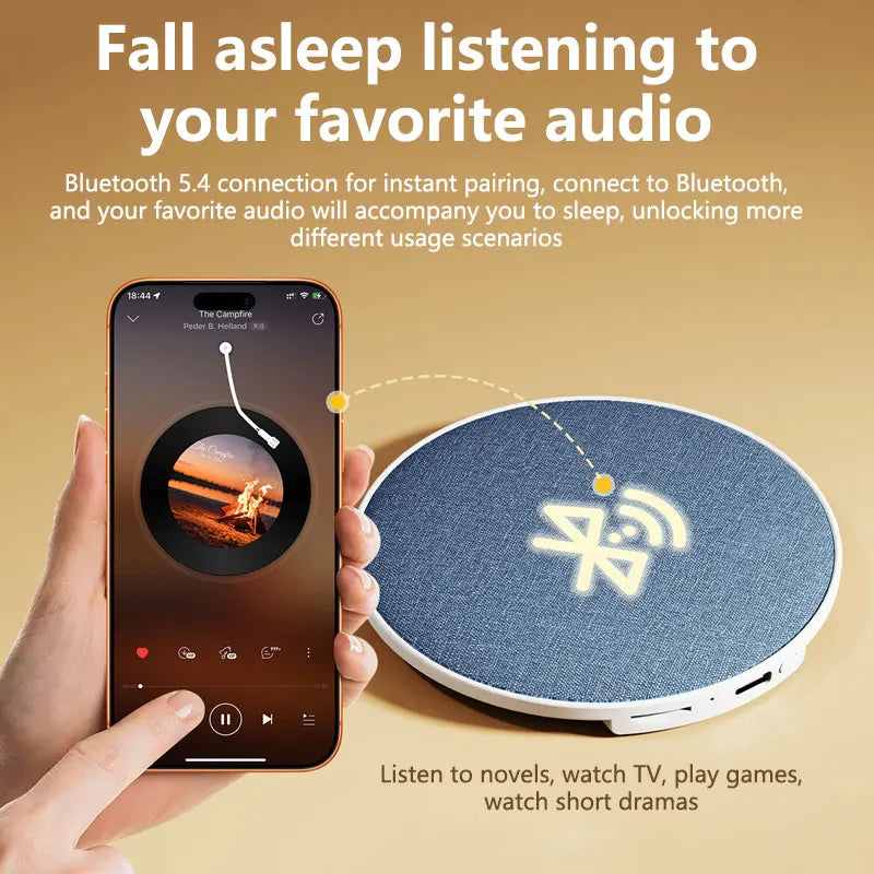 A hand holds a smartphone connected to a round, fabric-covered blue Bluetooth pillow speaker for sleep.
