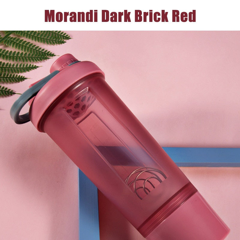 Dark brick red shaker bottle with a grey lid, carry handle, and interior mixing whisk.