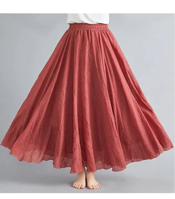 Rust-red maxi skirt with an elasticated waistband, featuring a voluminous, pleated, flowy design in textured fabric.