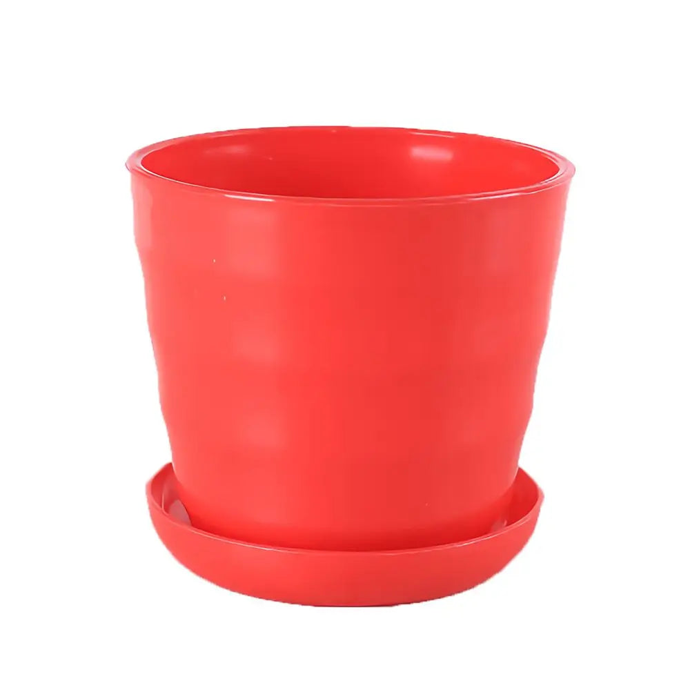 A bright red, cylindrical plastic flower pot with a matching saucer, featuring a decorative ribbed side texture.
