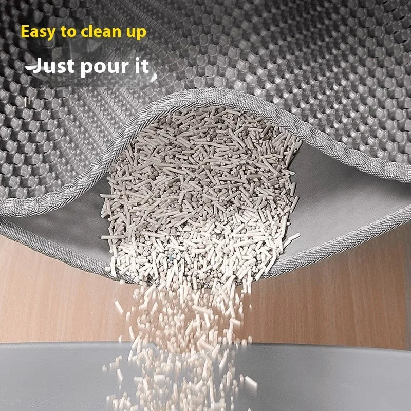 Grey, waterproof cat litter mat with a honeycomb surface, being tipped to pour trapped litter back into a tray.