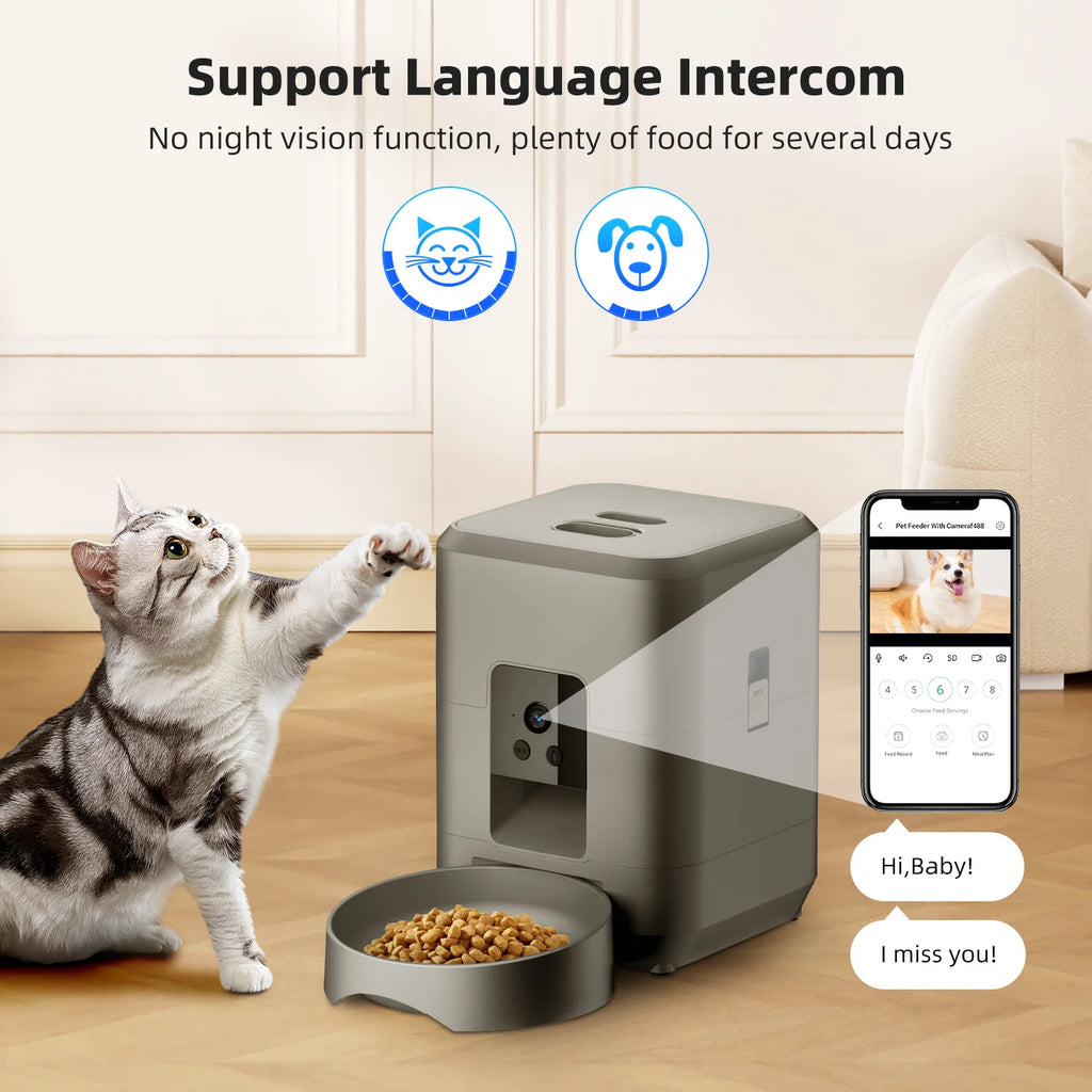 A grey automatic pet feeder with a built-in camera, shown with a cat and a smartphone app display.