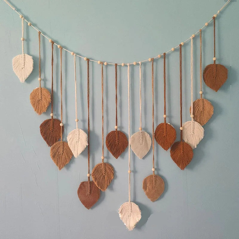 Boho macrame wall hanging featuring cream and brown leaf-shaped tassels accented with wooden beads on a string.