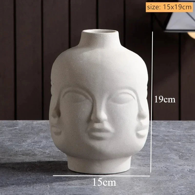 Off-white ceramic vase featuring a unique three-faced sculpted design, 15cm wide by 19cm tall.