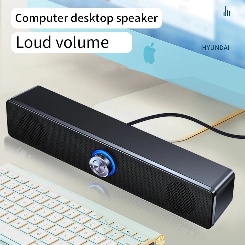 Sleek black wired USB stereo soundbar featuring a central volume dial with blue LED lighting on a computer desk.