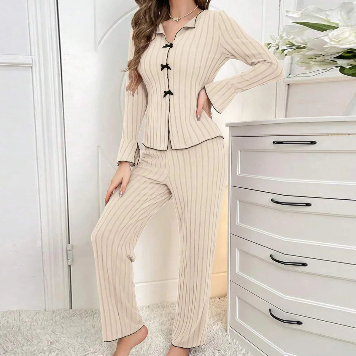 Beige ribbed loungewear set with a button-up top, black trim, and cute bow detailing on the front.