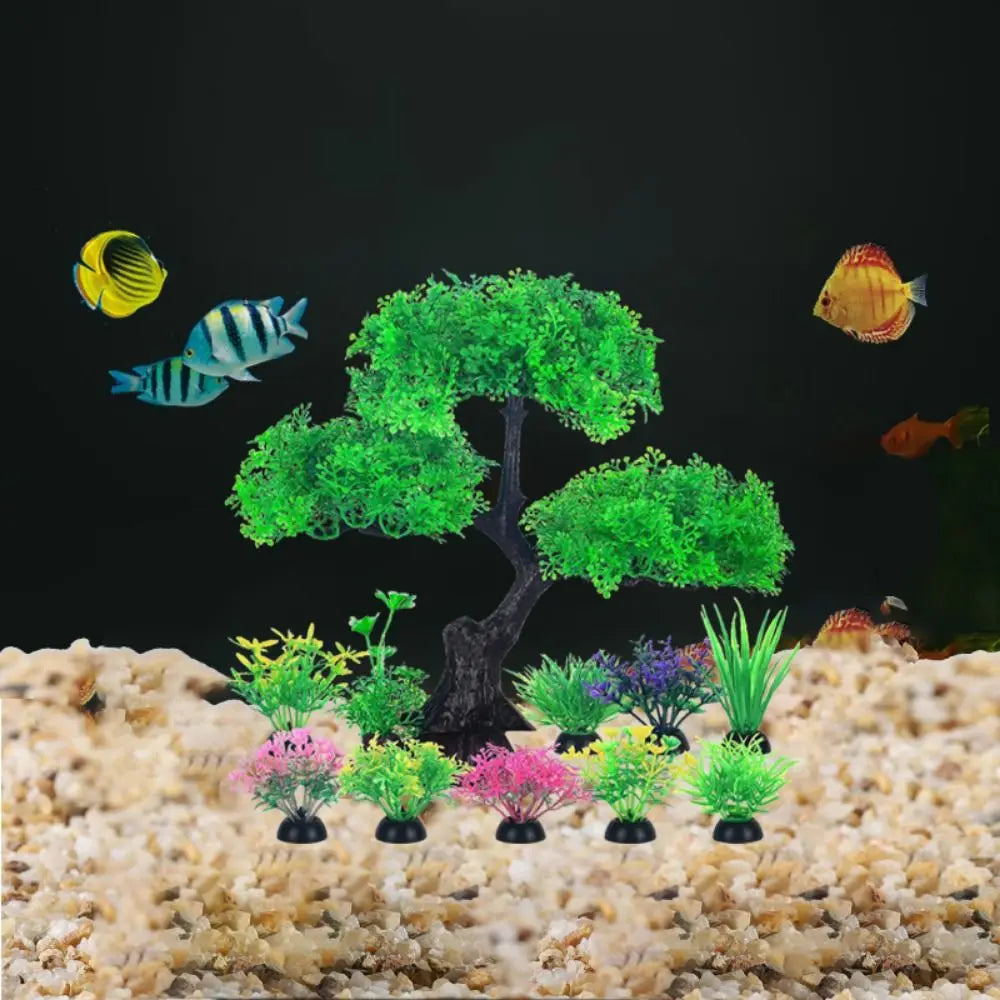Artificial bonsai tree and assorted colorful plastic aquarium plants on light gravel with swimming tropical fish.