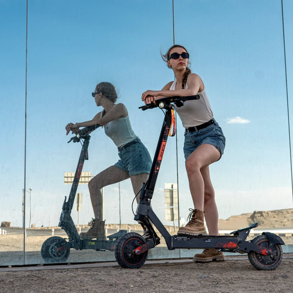 Black KuKirin G2 Ultra electric scooter with 10-inch tires and red accents, ridden by a woman.
