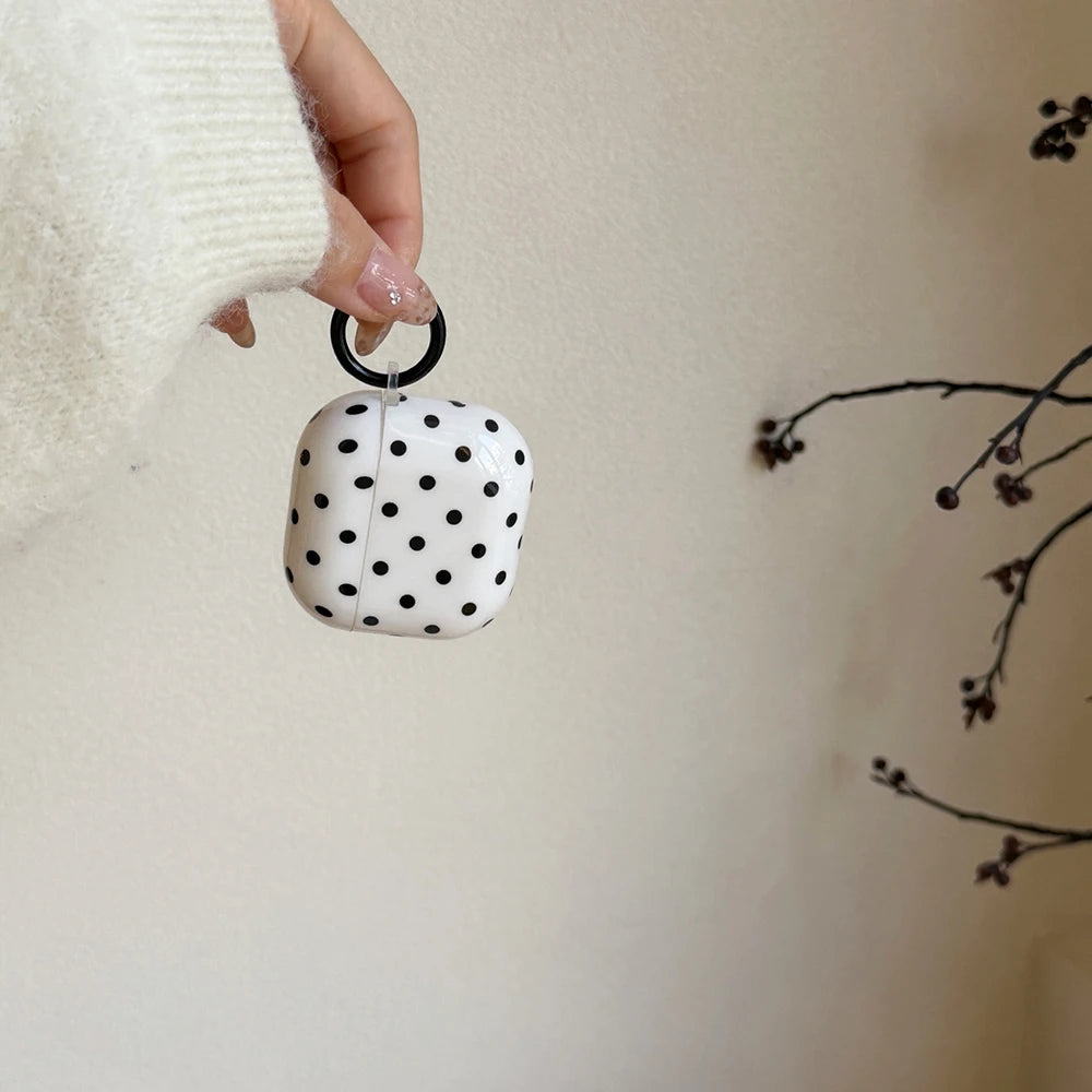 White and black polka dot glossy hard-shell AirPods case with a black attachment ring.