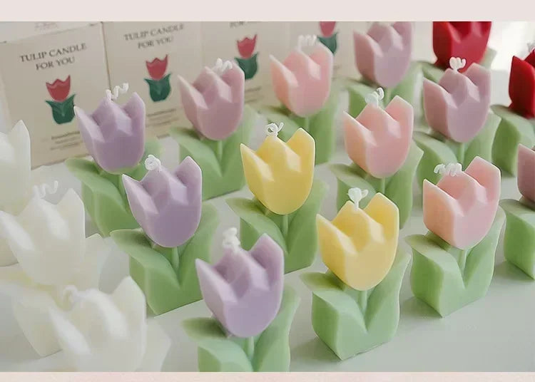 Assorted pastel tulip-shaped candles in white, yellow, pink, and purple, each featuring a green base and white wick.