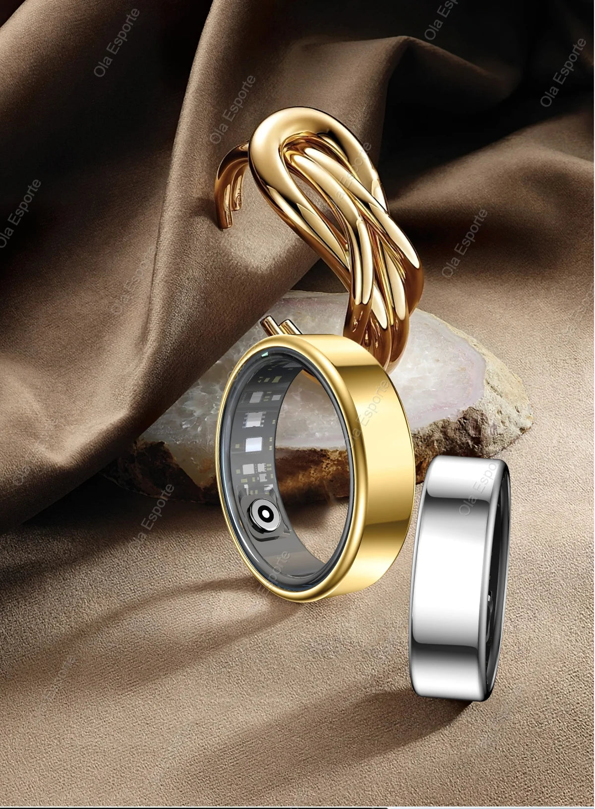 Gold and silver smart health rings with internal sensors, displayed on a brown fabric background.