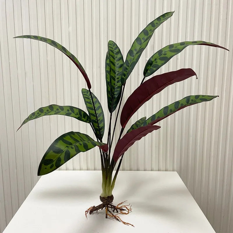 Artificial plant with long, spotted green leaves and deep red undersides, featuring exposed roots at the base.