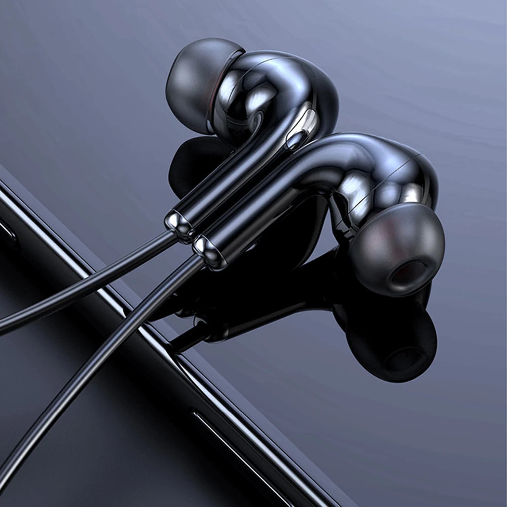 Glossy black magnetic wireless in-ear headphones with soft ear tips, resting on a dark reflective surface.