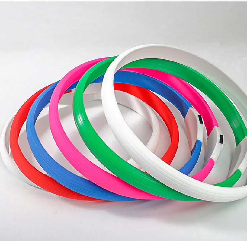 Stack of multicoloured, waterproof LED dog collars in white, green, pink, blue, and red on a white background.