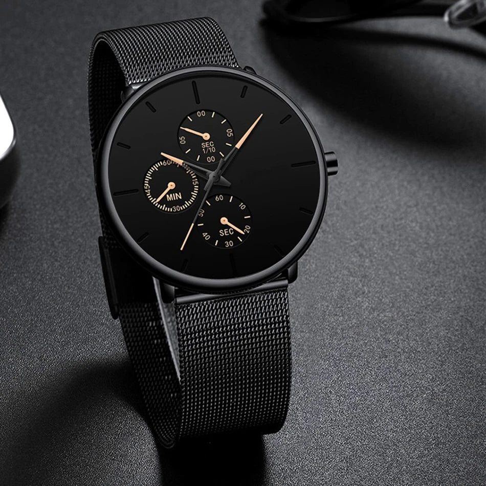 Ultra-thin men's watch in all-black stainless steel with a mesh strap and minimalist black dial with gold accents.