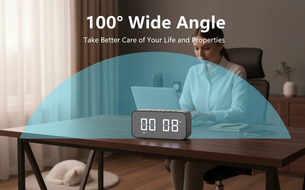 Grey plastic digital clock camera with 100-degree wide-angle lens on a wooden desk.