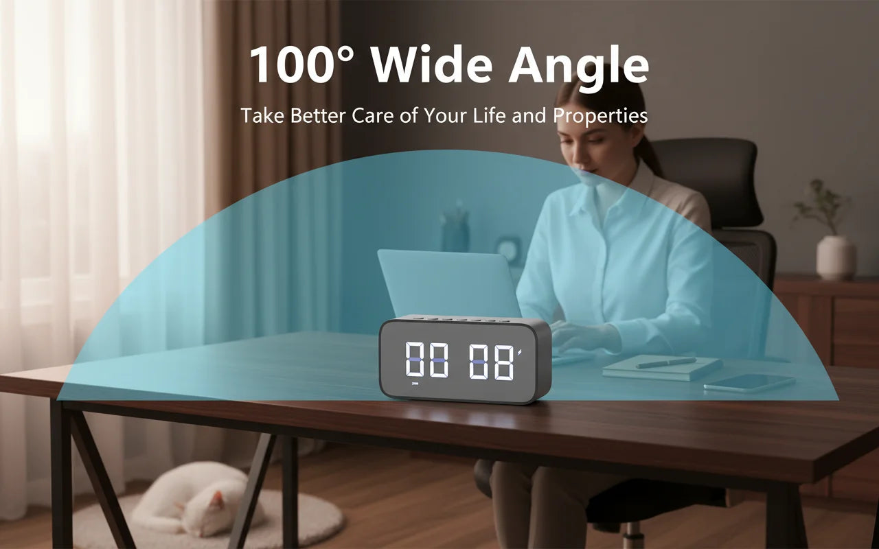 Grey plastic digital clock camera with 100-degree wide-angle lens on a wooden desk.