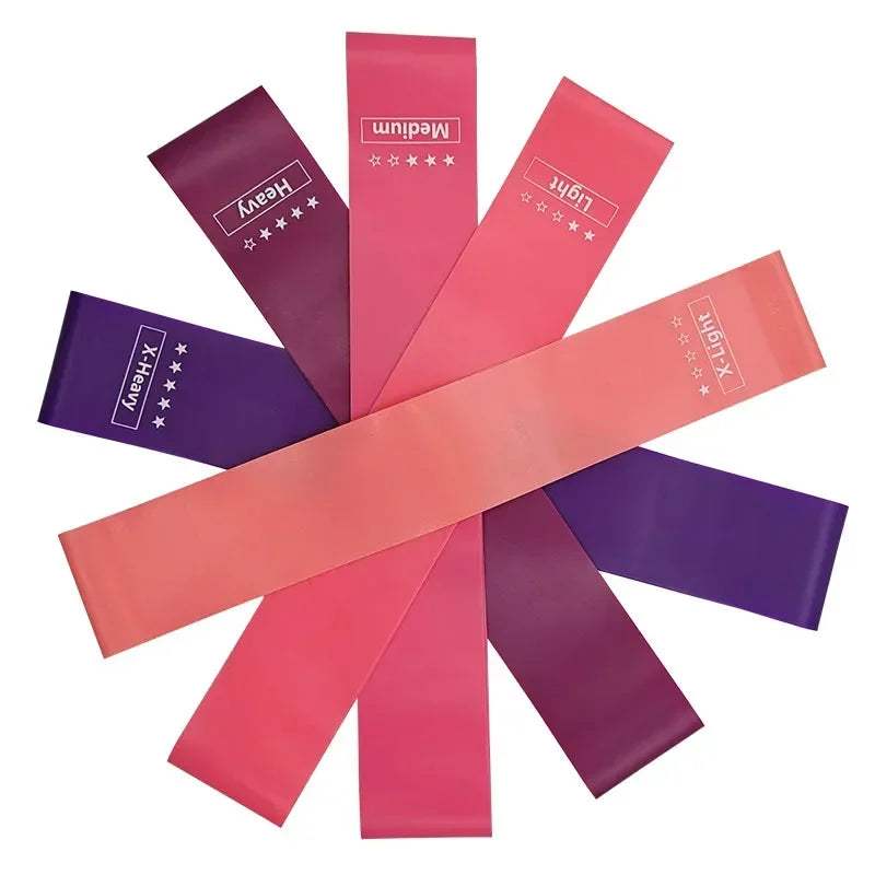 A set of five resistance bands in a gradient of pink to purple, labelled by resistance from X-Light to X-Heavy.