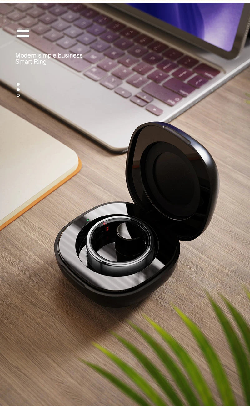 Sleek black smart health monitoring ring inside an open charging case, displayed on a wooden desk.