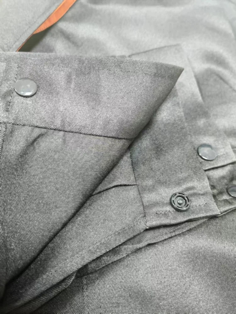Close-up of grey, heavy-duty workshop coveralls featuring reinforced seams and durable press-stud button fastenings.
