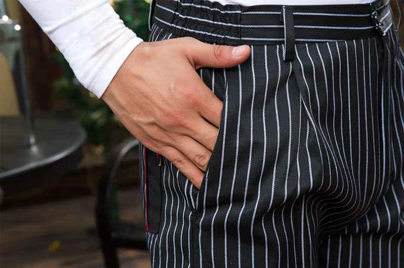 Black chef trousers with white vertical pinstripes, featuring an elasticated waistband and side pockets.