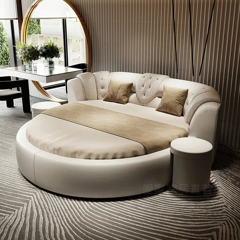 Modern, circular cream leather double bed with a tufted, curved headboard and matching side stool.