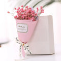 A bouquet of pink gypsophila flowers in pink wrapping with a 'Thank you' label and decorative ribbon next to a box.