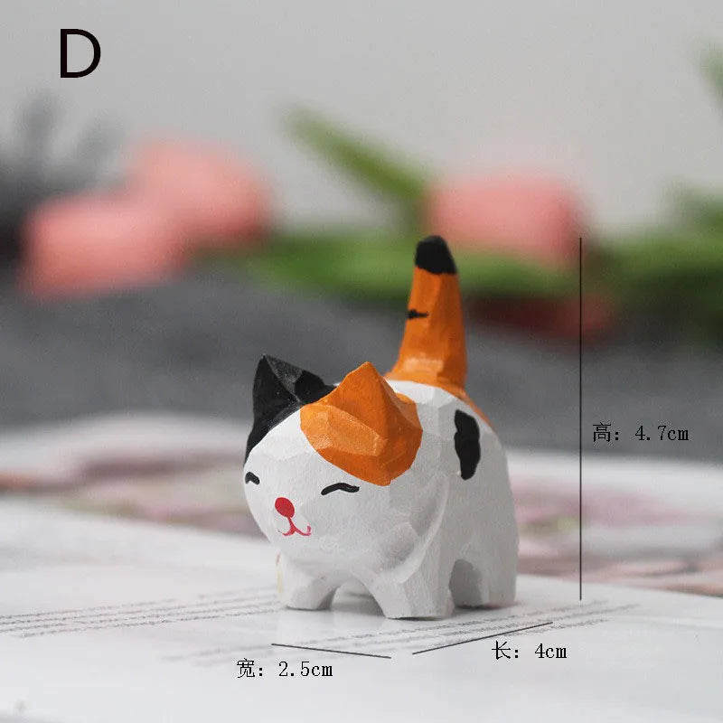 Small, hand-carved wooden calico cat figurine with a smiling face, upright tail, and faceted finish.