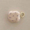 Cream glossy AirPods case with purple bow pattern and yellow keychain ring. Compatible with AirPods.
