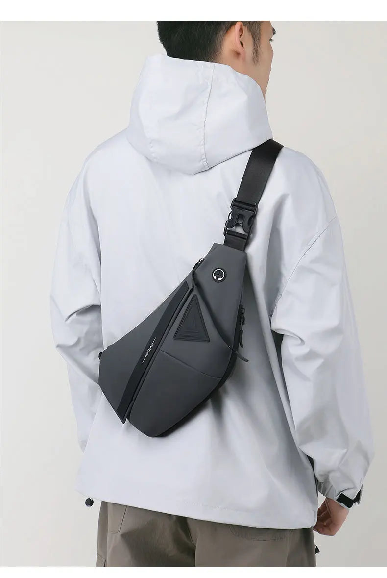 A man wearing a charcoal grey, slim-fit anti-theft crossbody sling bag with a secure buckle strap and earphone port.