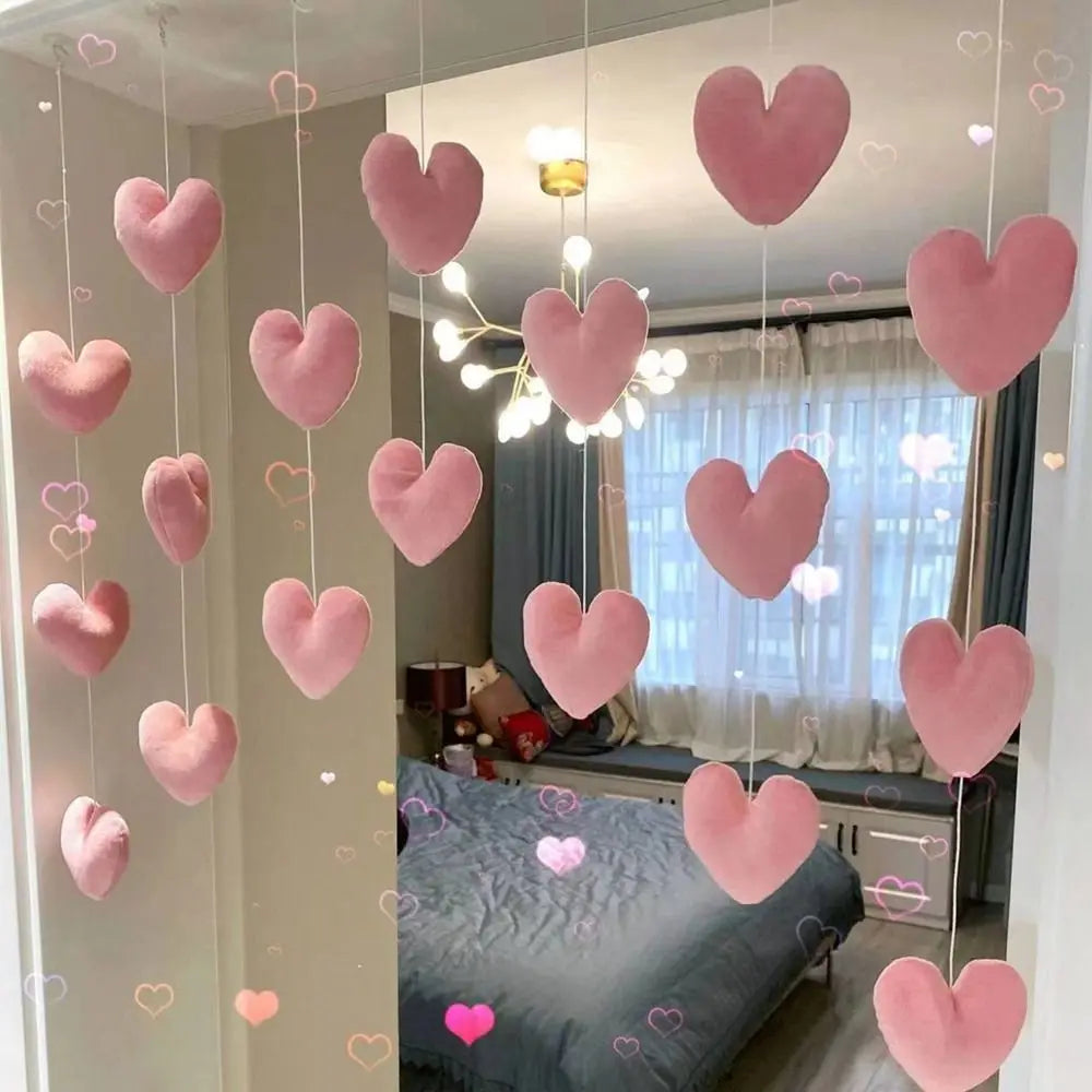 Hanging strings of plush, pink fabric hearts used as decorative bedroom room dividers or wall decor.