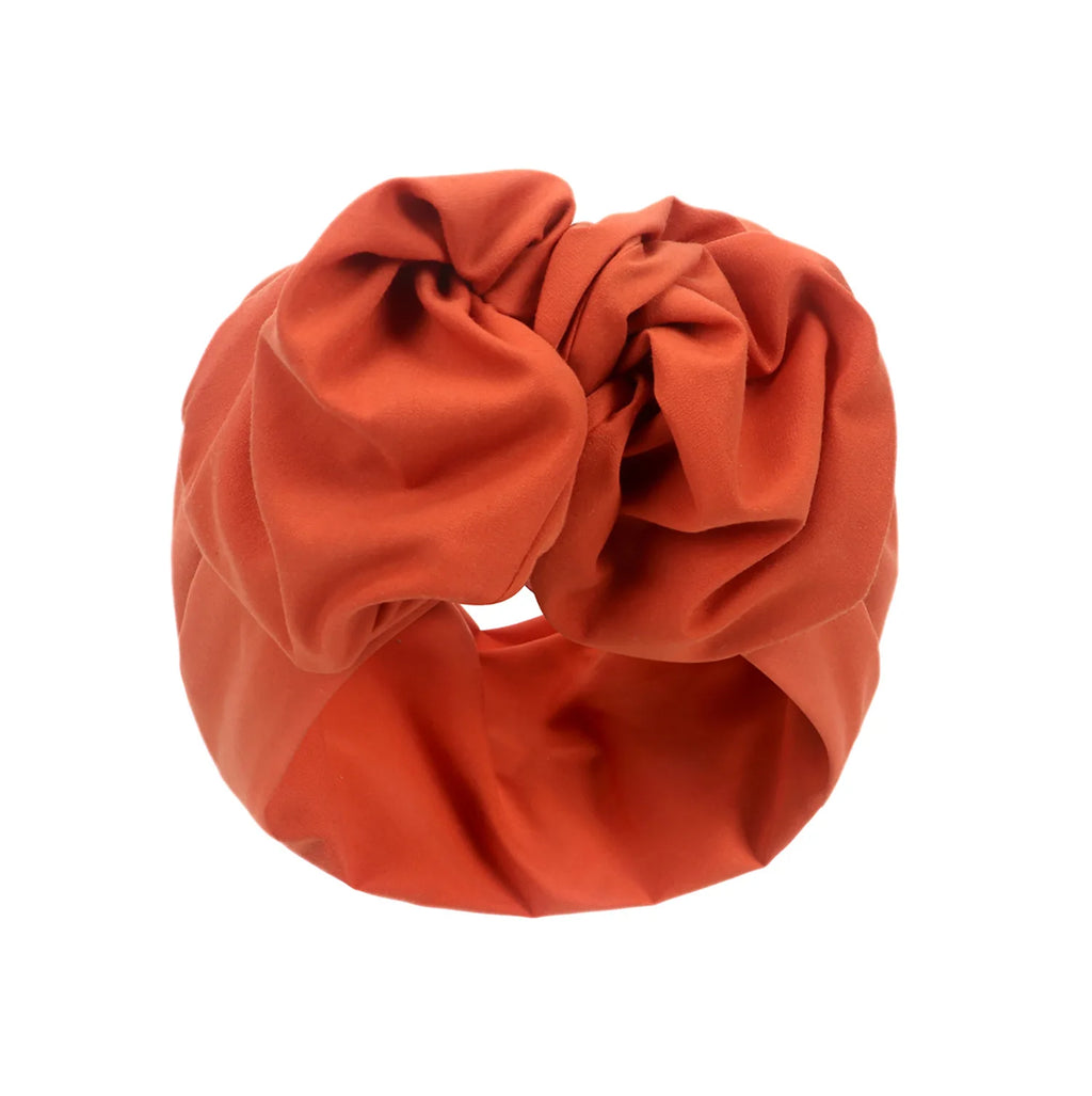 Burnt orange French vintage style turban hat featuring a gathered knotted front design.
