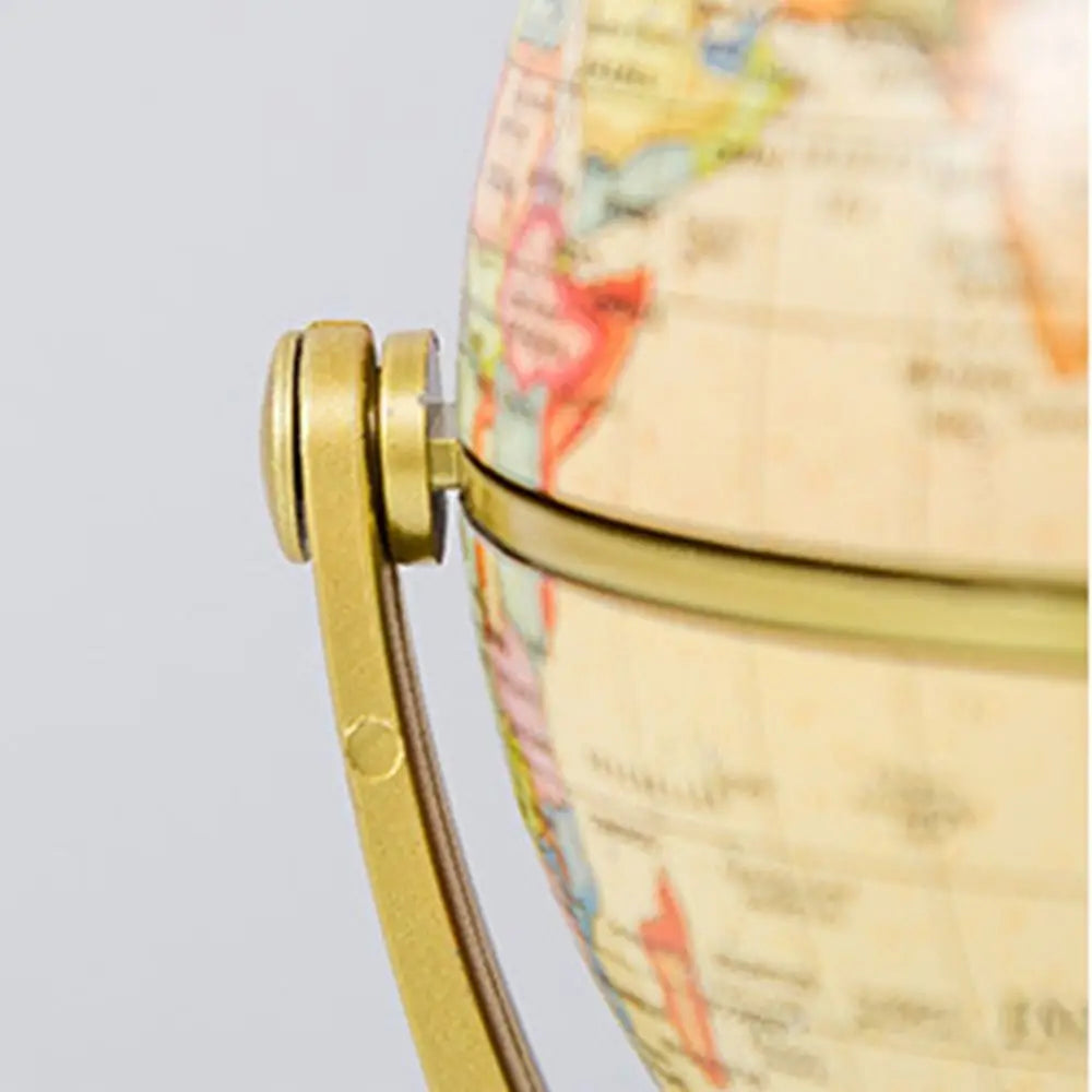 Close-up of a vintage-style world globe featuring an antique cream map and a brushed gold metal stand.