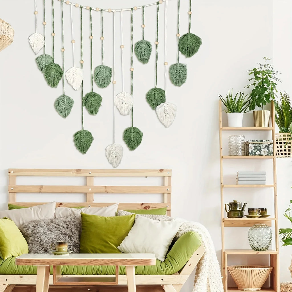 Boho-style wall hanging featuring sage green and cream macramé leaves, wooden beads, and cascading cotton cord.