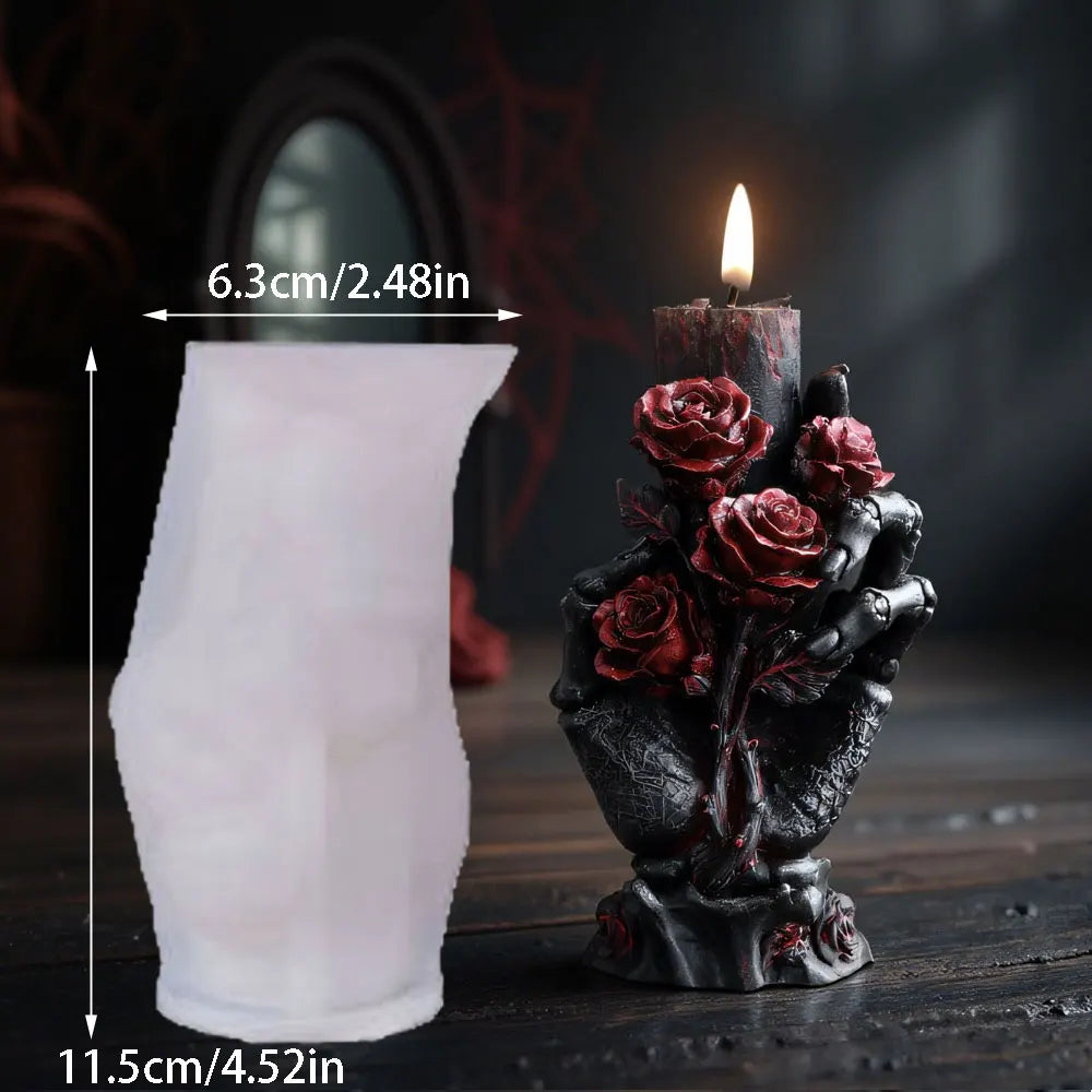 Translucent white silicone candle mold next to a black skeleton hand holding red roses pillar candle with lit flame.