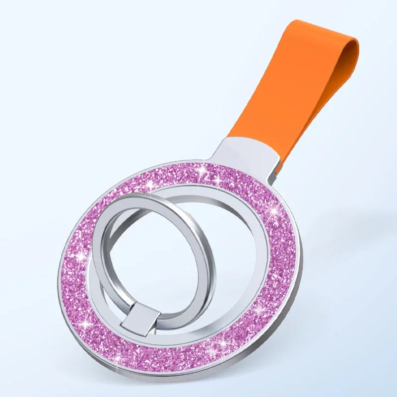 A silver, glittery purple circular phone ring holder with an orange loop strap on a light blue background.