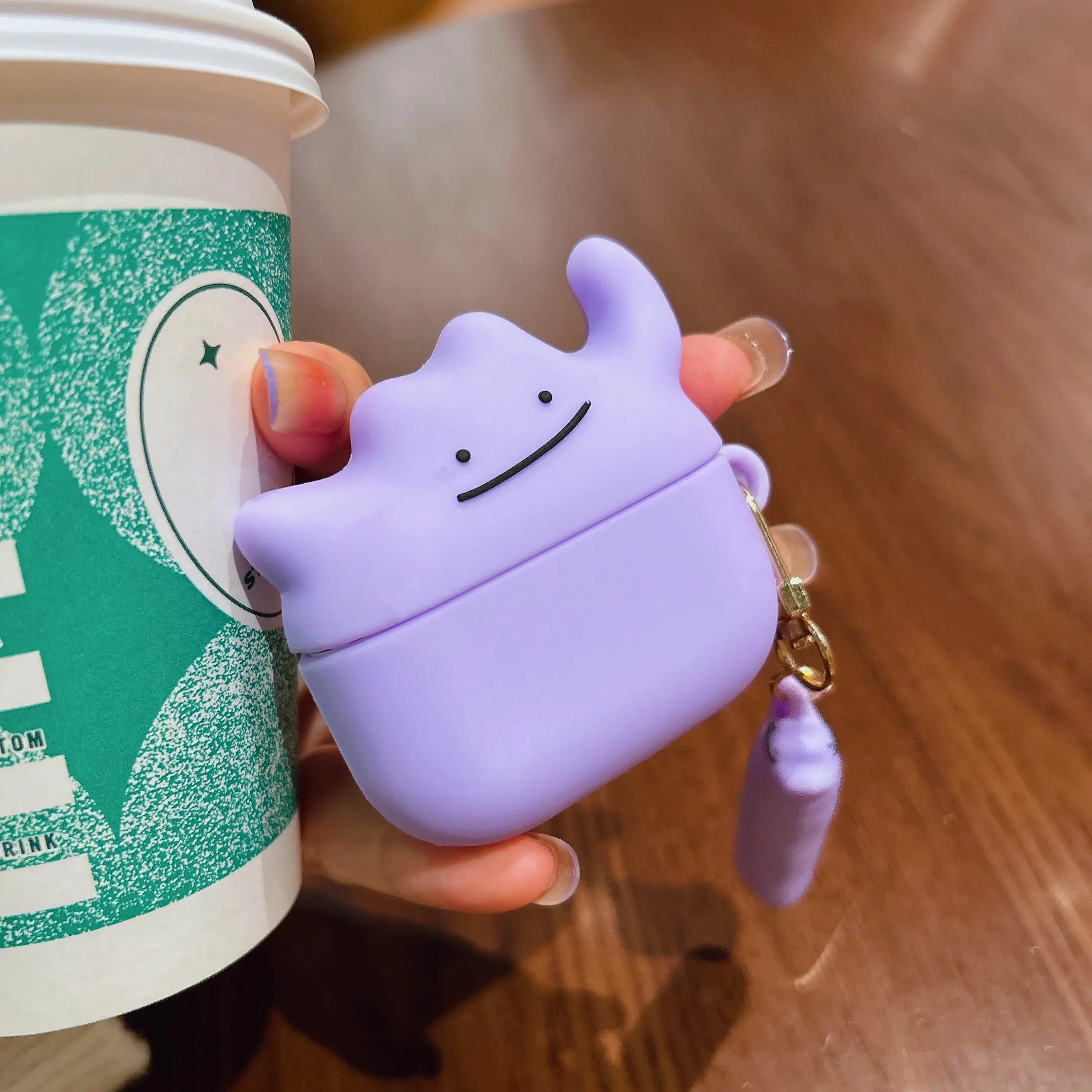 Purple silicone AirPods case featuring a Ditto character design with a matching charm.