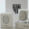 Scented candle in a clear glass jar with a white label, standing beside its matching minimalist white presentation box.