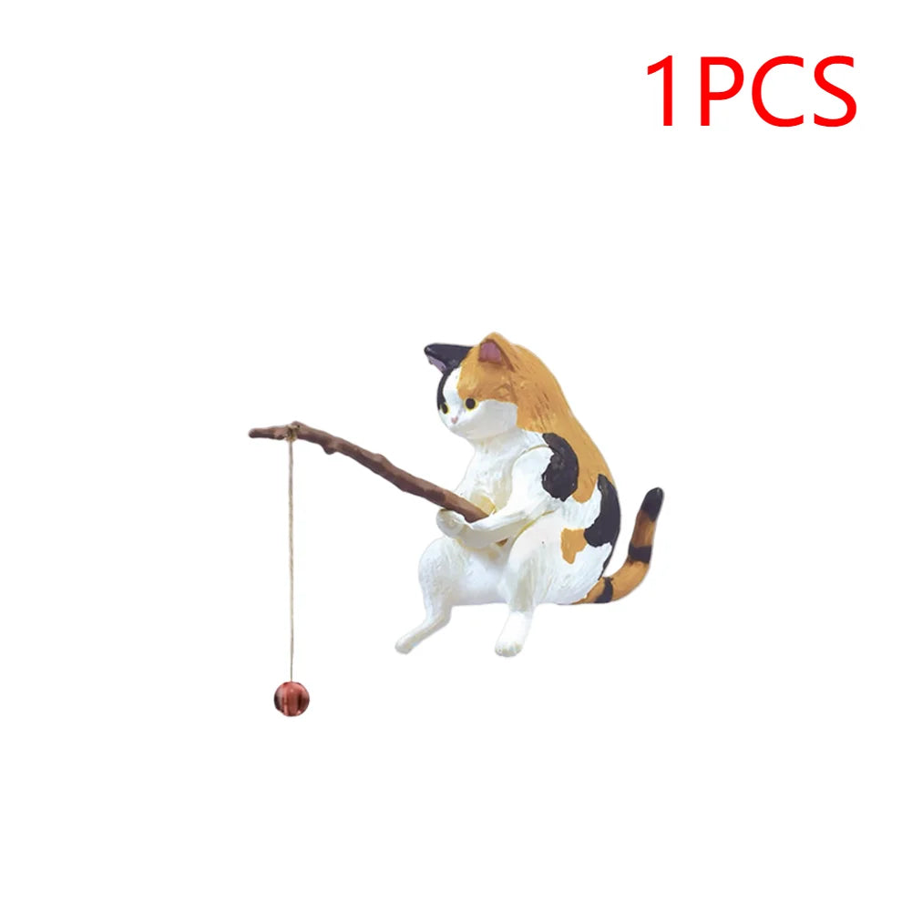 A calico cat ornament holding a small wooden fishing rod with a dangling line and red bobber.