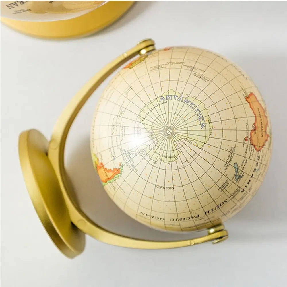 Vintage-style cream world globe on a gold metal stand, featuring a detailed map view of Antarctica.