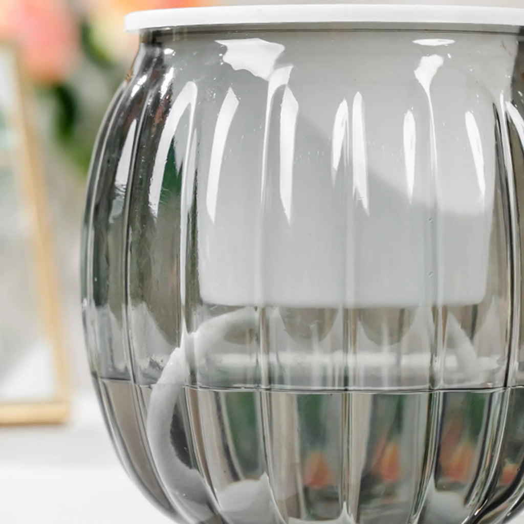 Modern clear ribbed glass self-watering pot with a white inner planter and absorbent wick for plant hydration.