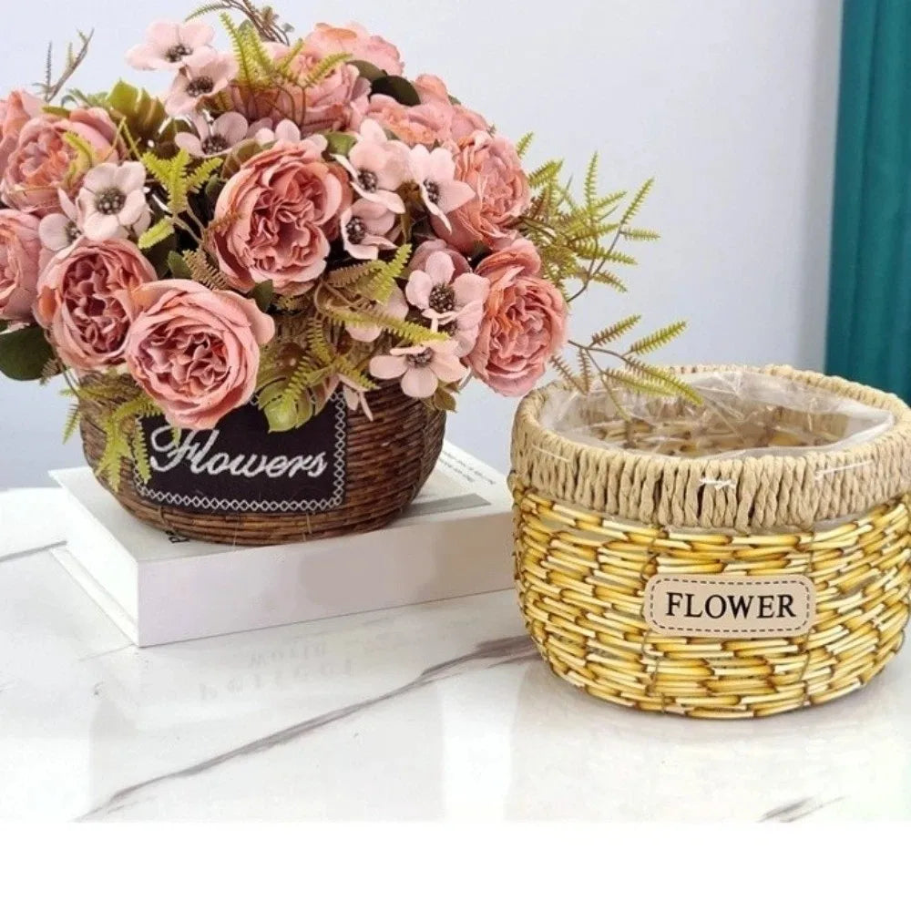 Two round, woven rustic baskets on a white table: one holds pink artificial flowers, the other is empty and tan-toned.