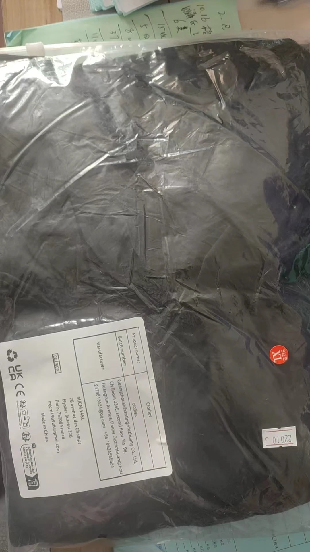 Black garment in size XL, sealed in protective plastic packaging with product label.