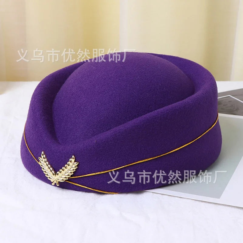 Purple felt vintage-style stewardess pillbox hat with a gold trim and a gold leaf-shaped brooch detail.